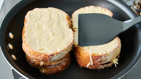 Pressing down on the sandwiches in a pan.