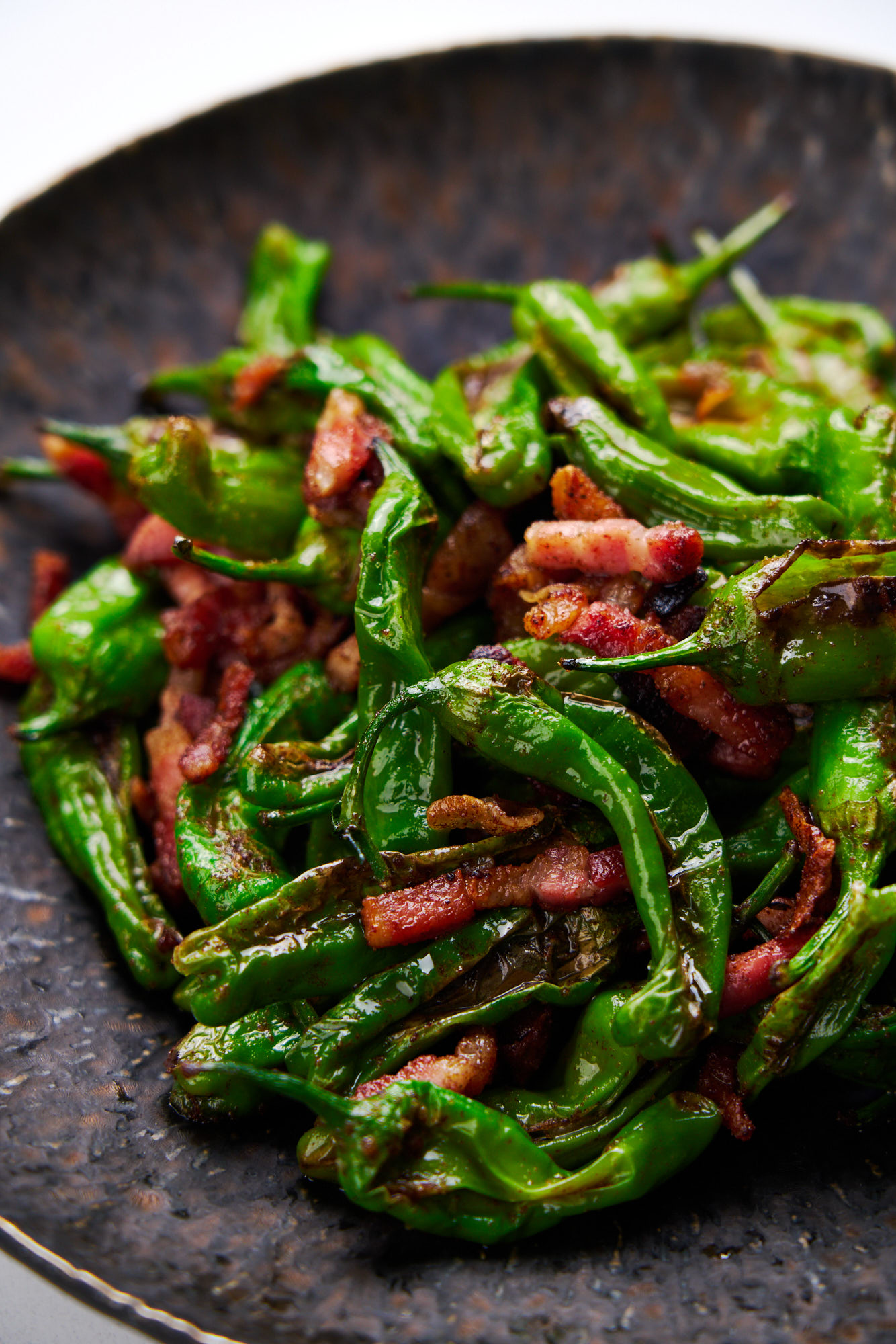 A plate of Pan-Roasted Shishito Peppers with Crispy Pancetta