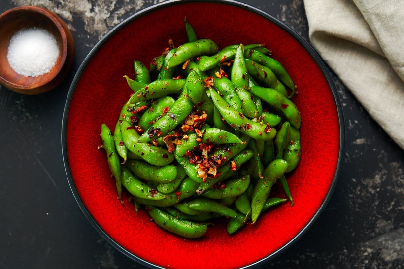 Green Spicy Edamame in a red lacquer bowl.