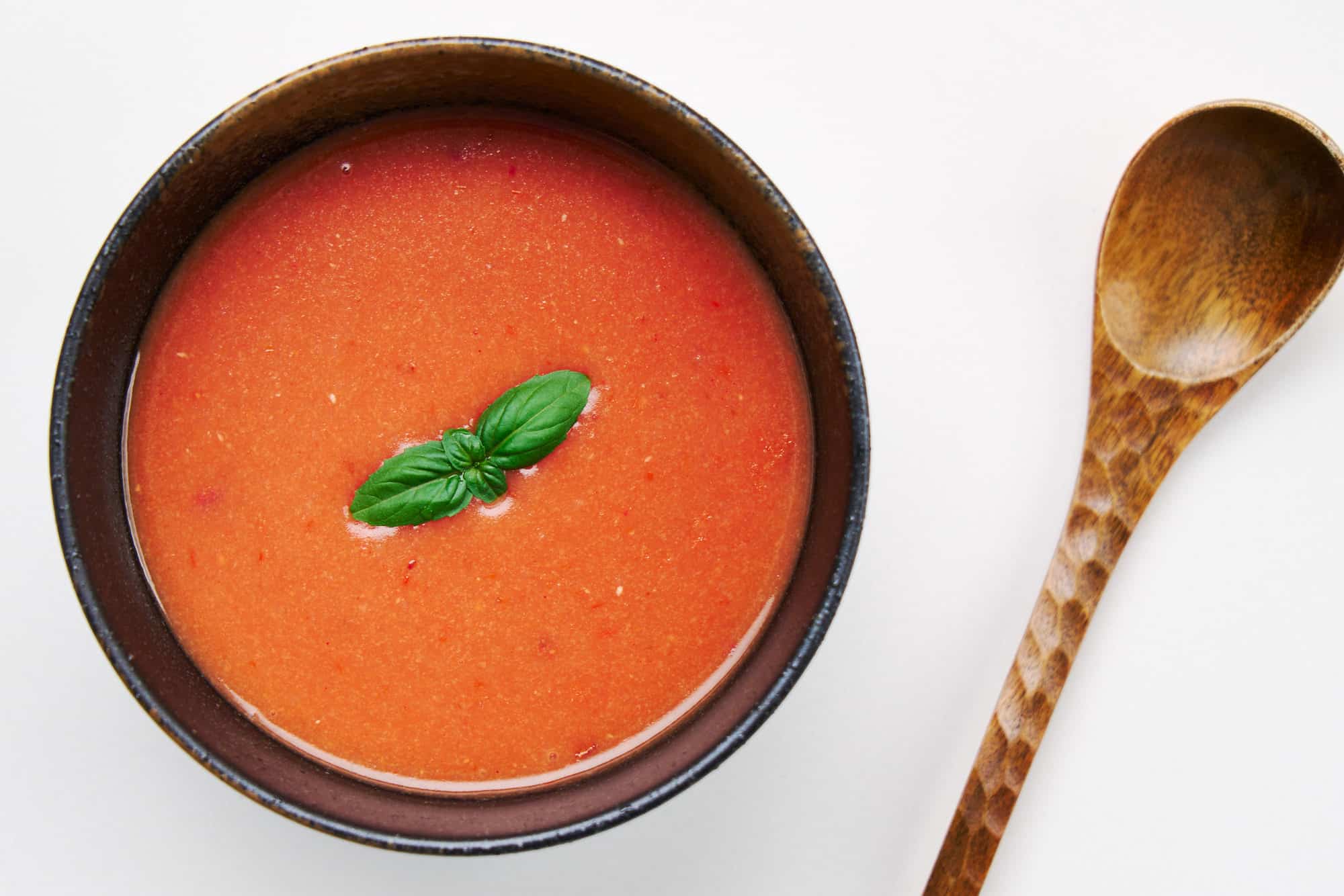 An artful balance of creamy and tangy, the Tomato Rice Soup, cradled in a dark earthenware bowl.