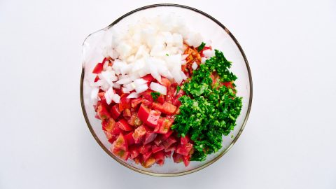 Kimchi, tomatoes, onions and cilantro in a bowl.