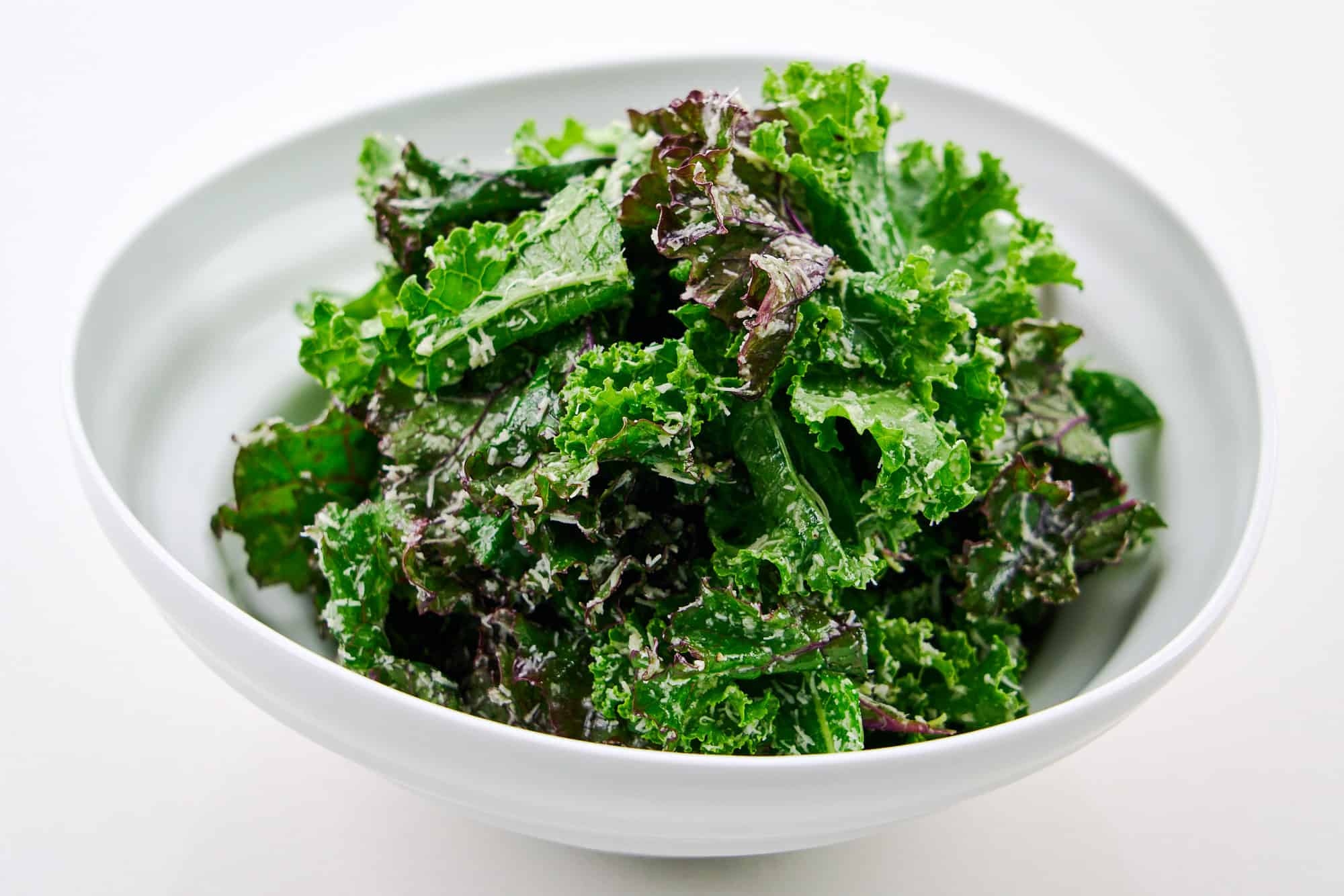 Side angle shot of the salad, highlighting layers of kale leaves with a generous sprinkle of Pecorino Romano.