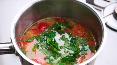 Tomato miso soup with fresh green shiso leaves.