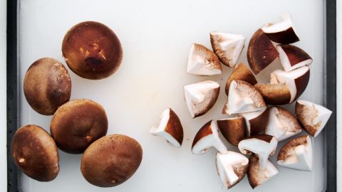 Quartered shiitake mushrooms on a cutting board.