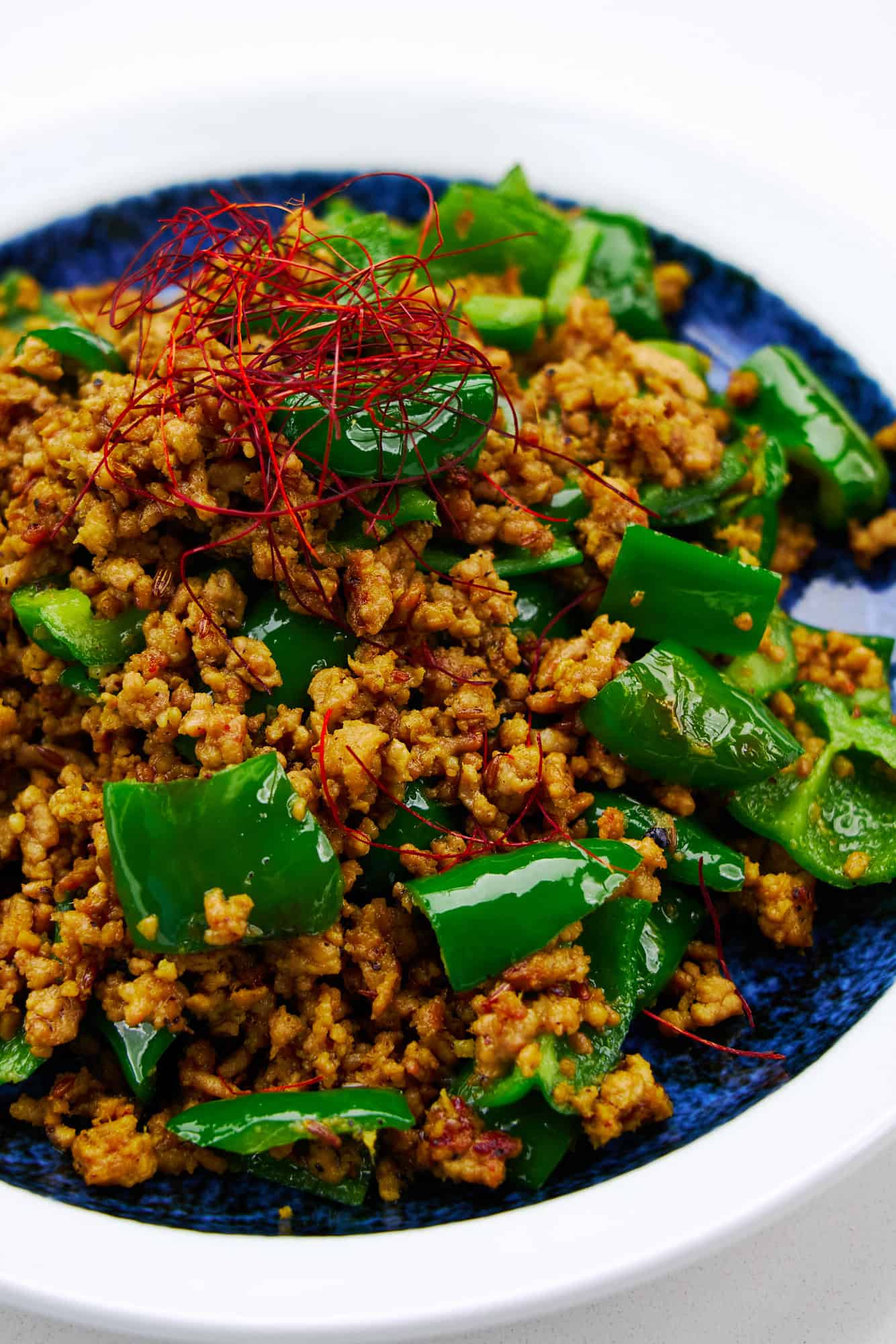 Green chili pepper dry curry on a blue plate. with chili threads.