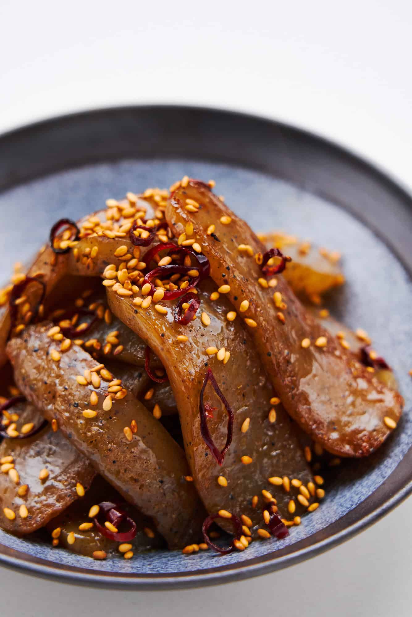 Spicy pan-fried konnyaku glazed in a savory sweet sauce with toasted sesame seeds and chili flakes.