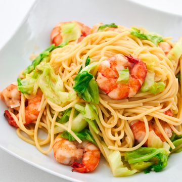 A plate of spaghetti with cabbage and shrimp.
