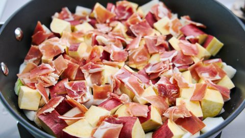 Sweet potatoes, onions, and ham in a skillet.