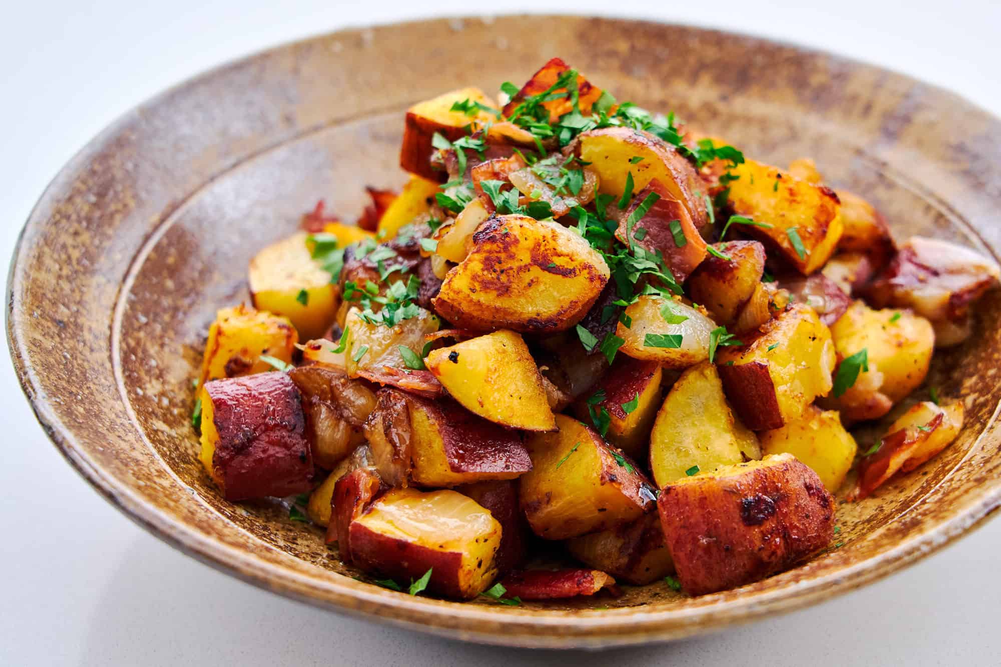 Caramelized sweet potatoes, onions, and ham in a bowl.