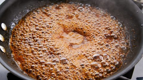 Boiling the sauce to reduce it.