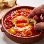 Dipping crusty bread in Piperade.