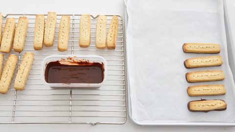 Shortbread fingers getting dipped in chocolate.