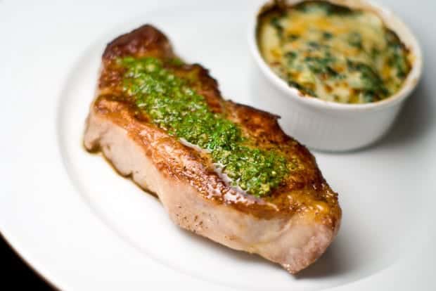 A ribeye steak anointed with chimichurri sauce.