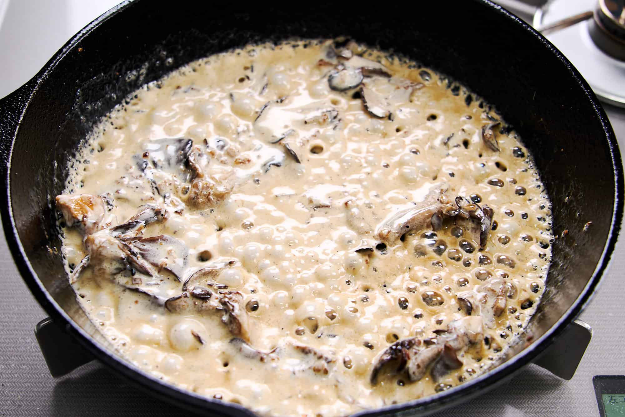 Reducing the cream and wine in the mushrooms.