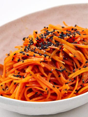 A side view of Carrot Kinpira, showing off its glossy strands and bold black sesame accents.