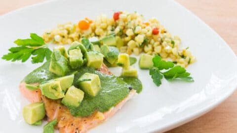 Colorful salmon topped with green salsa and avocado.