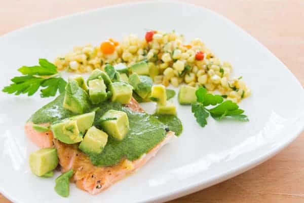 Colorful salmon topped with green salsa and avocado.
