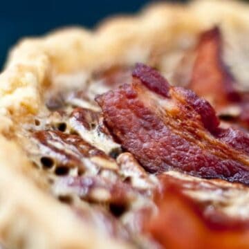 A slice of bacon on top of a pecan pie.