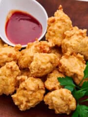 A stack of crispy chicken nuggets with spicy dipping sauce.