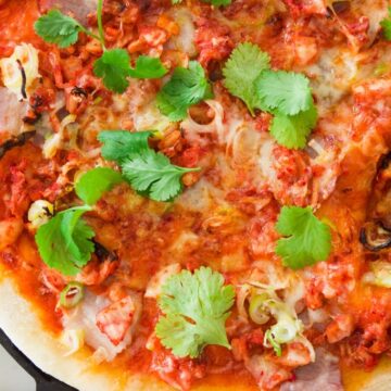 Closeup of kimchi and pork belly pizza.