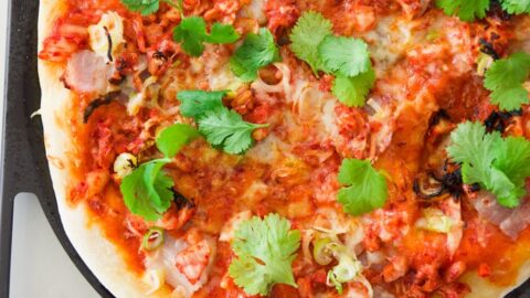 Closeup of kimchi and pork belly pizza.
