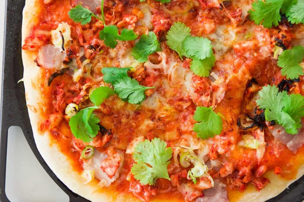 Closeup of kimchi and pork belly pizza.