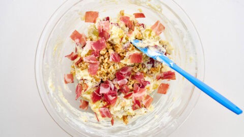 Adding the ham and walnuts to the potato salad.