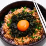 A bowl of spicy Korean tuna with rice and an egg yolk.