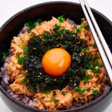 A bowl of spicy Korean tuna with rice and an egg yolk.