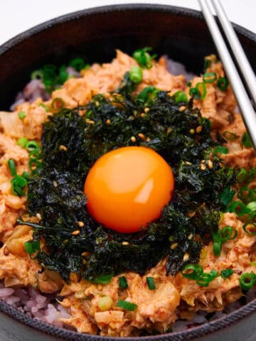 A bowl of spicy Korean tuna with rice and an egg yolk.