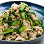 Tight angled shot of the plated lemon pepper chicken salad, showcasing glossy chicken strands, cucumber crunch, and black pepper specks.