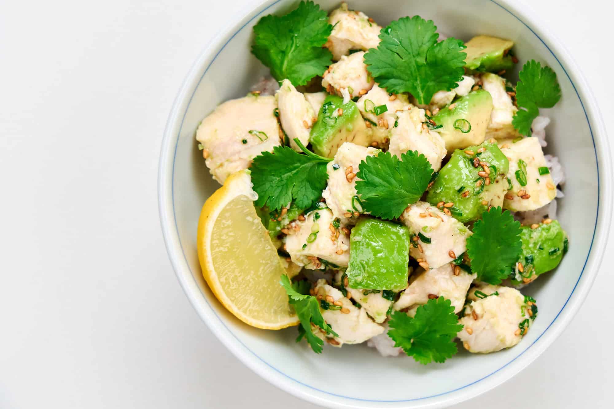 Chicken and avocado sprinkled with cilantro and served with a lemon wedge.