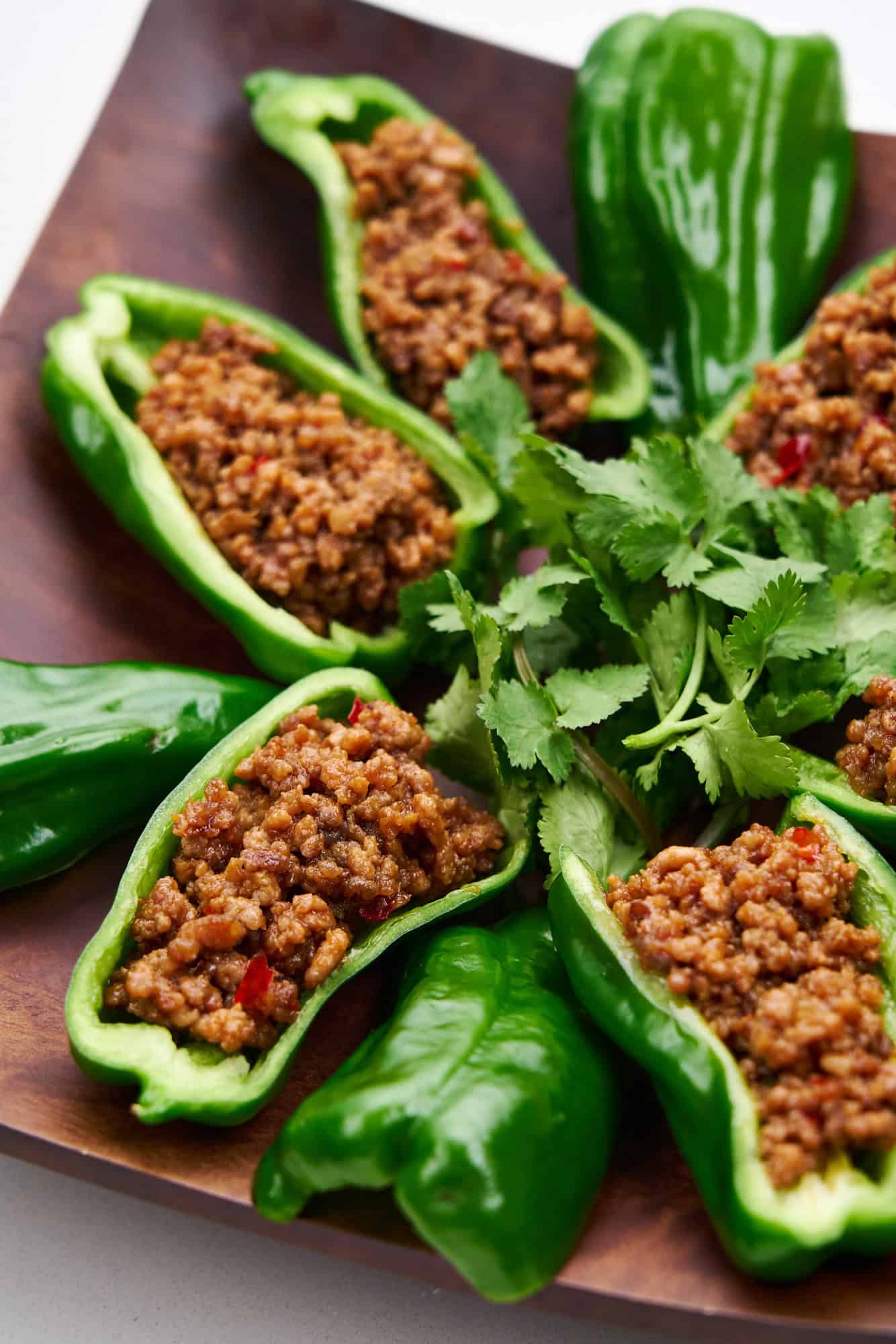 Spicy stuffed peppers arranged on a square platter.