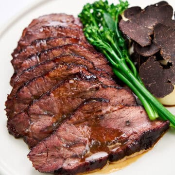 Slices of braised beef cheeks with truffle and broccolini.
