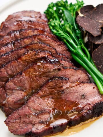 Slices of braised beef cheeks with truffle and broccolini.