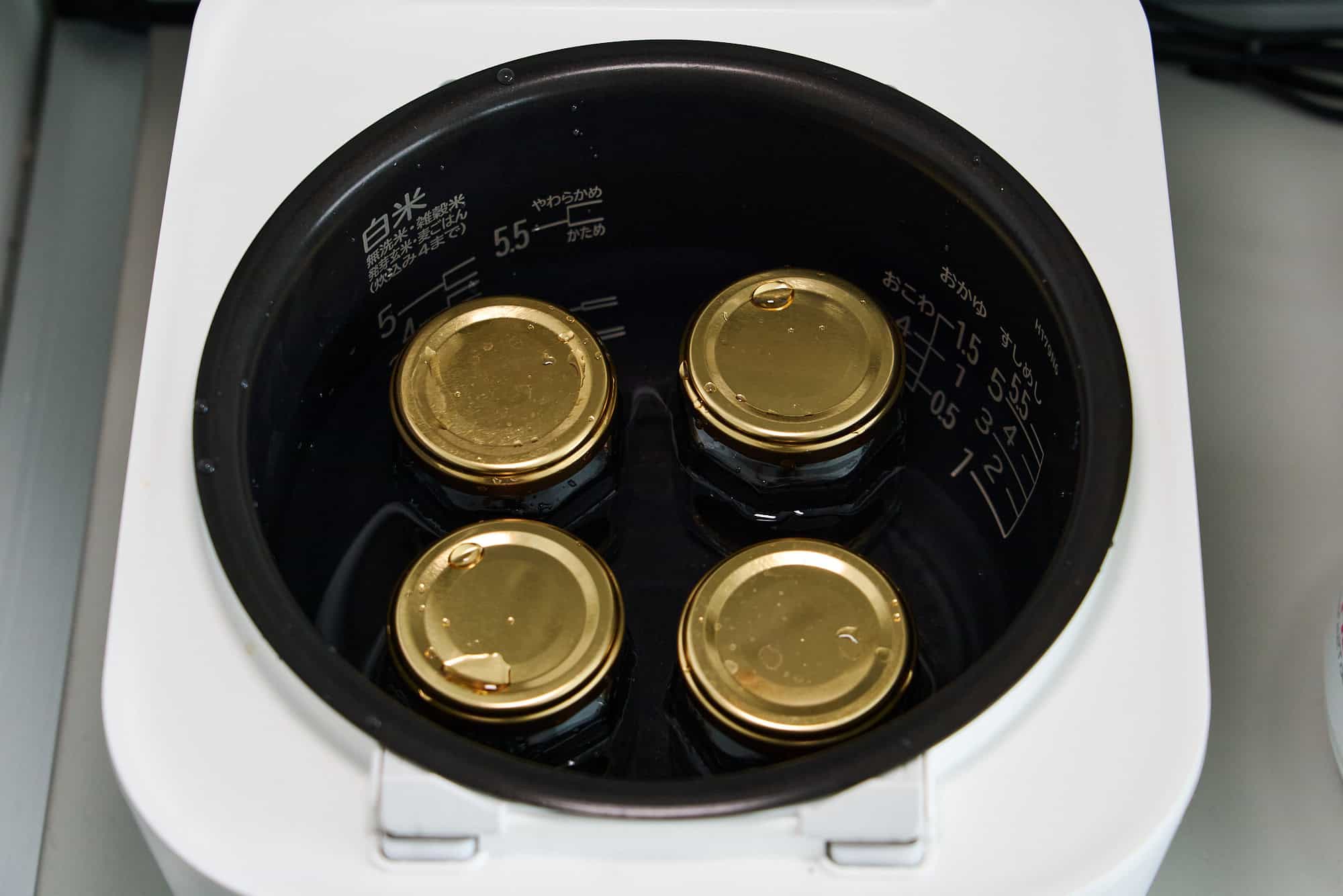 Jars filled with amazake submerged in a water bath.