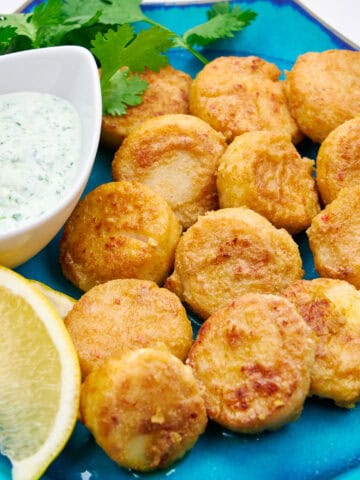 A plate of crispy, juicy pan fried scallops with a cool cilantro yogurt dipping sauce.