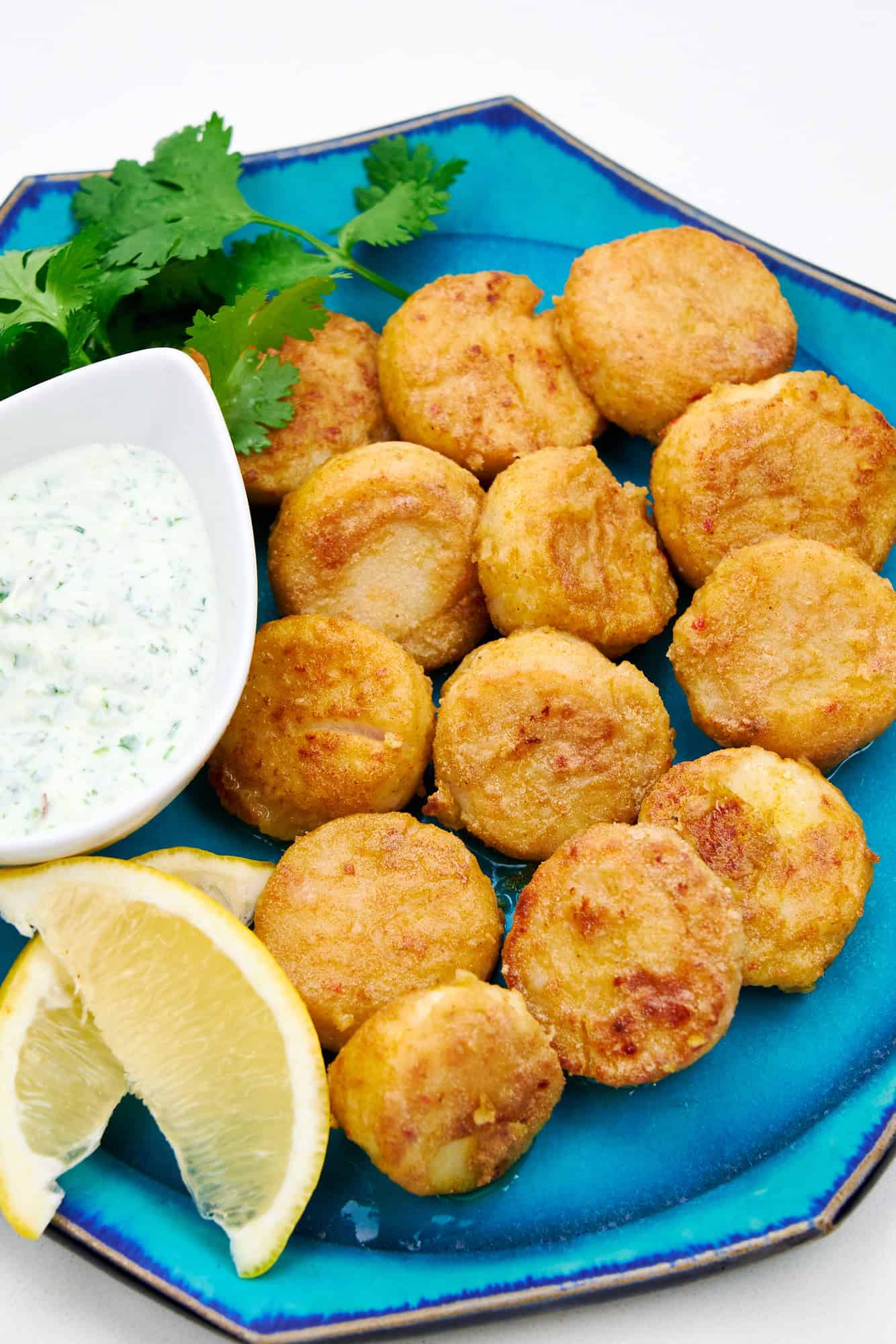 A plate of crispy, juicy pan fried scallops with a cool cilantro yogurt dipping sauce.