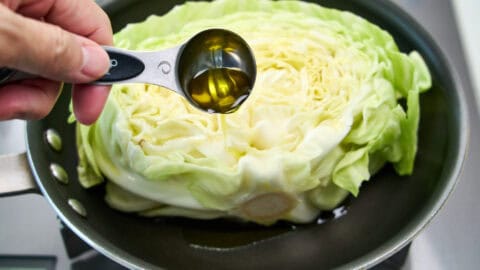 Adding olive oil to the cabbage.