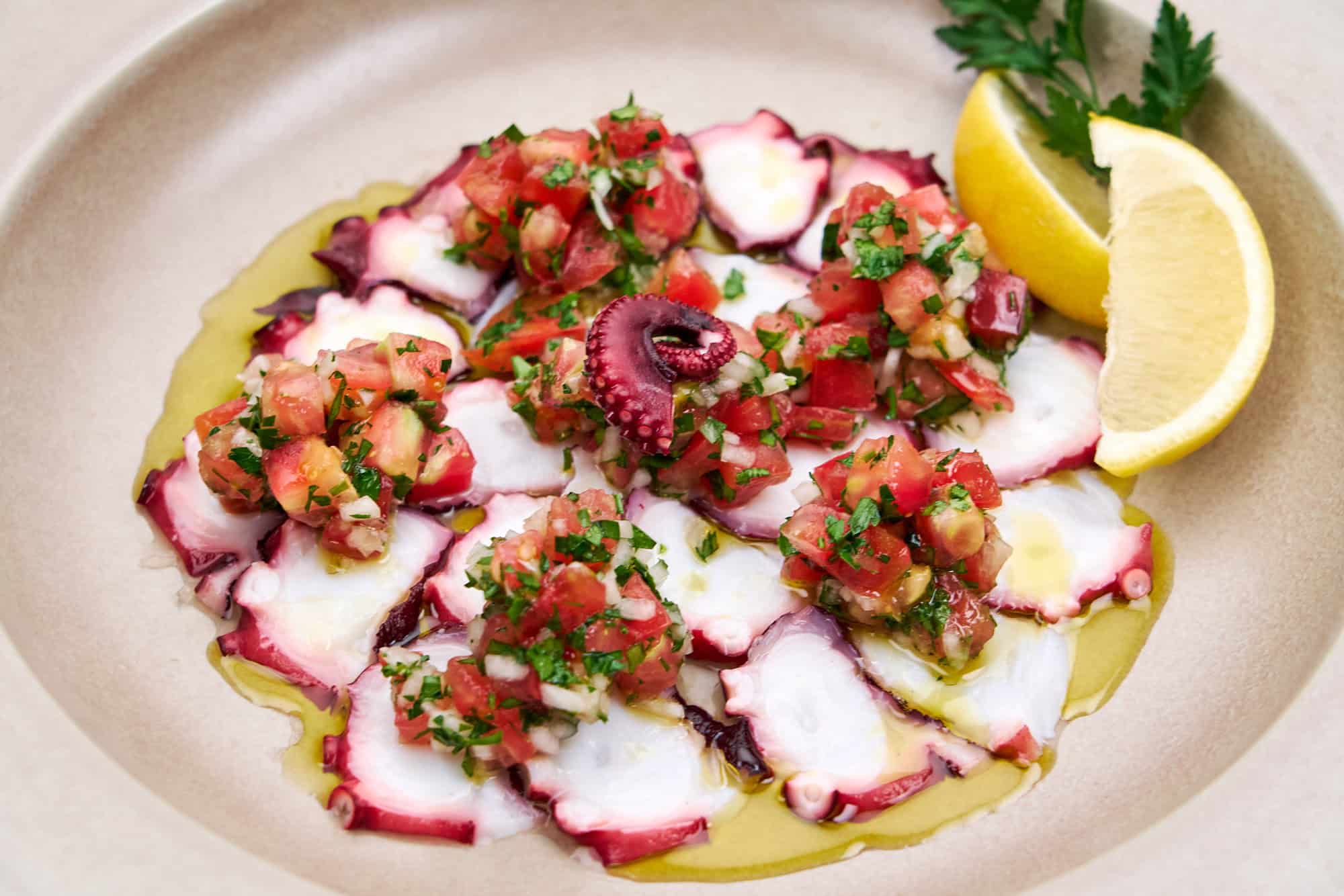 Cooked octopus dressed with tomato, onion, lemon and olive oil.