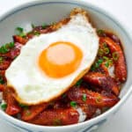 Smoked sausage, egg and rice in a bowl with scallions.
