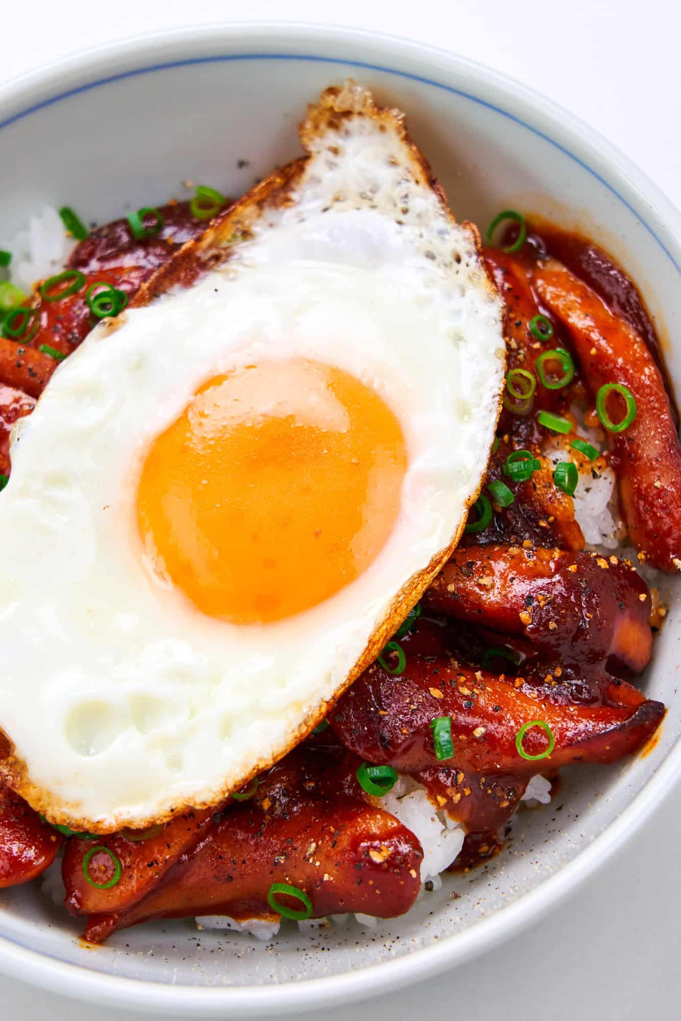 Smoked sausage, egg and rice in a bowl with scallions.