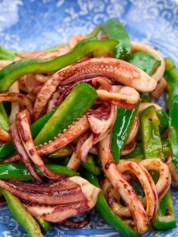 Closeup view of a plate of succulent squid and tender, crisp green bell peppers.