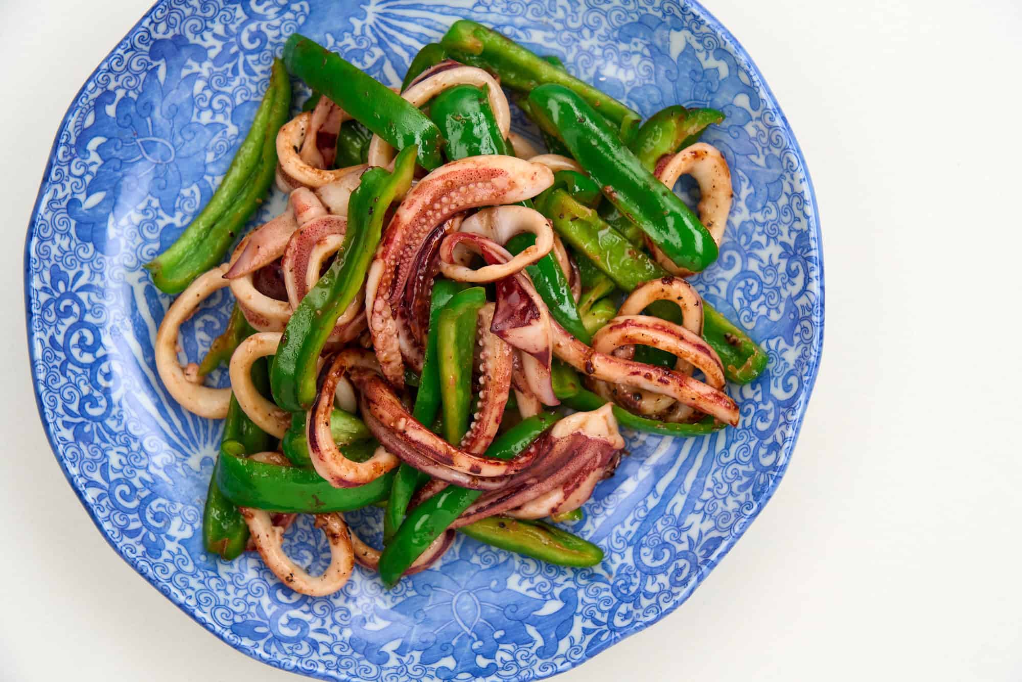 A plate of succulent squid and tender, crisp green bell peppers from above.