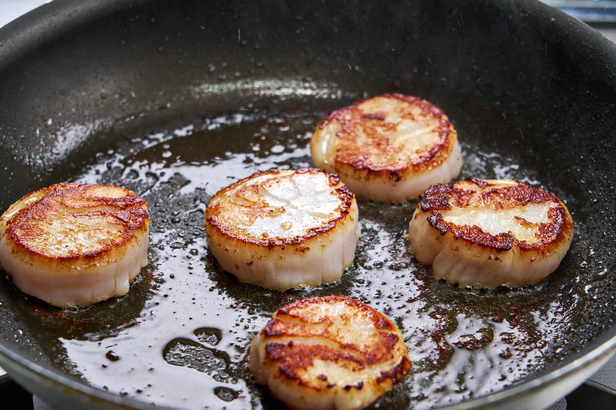 Scallops developing a golden crust.