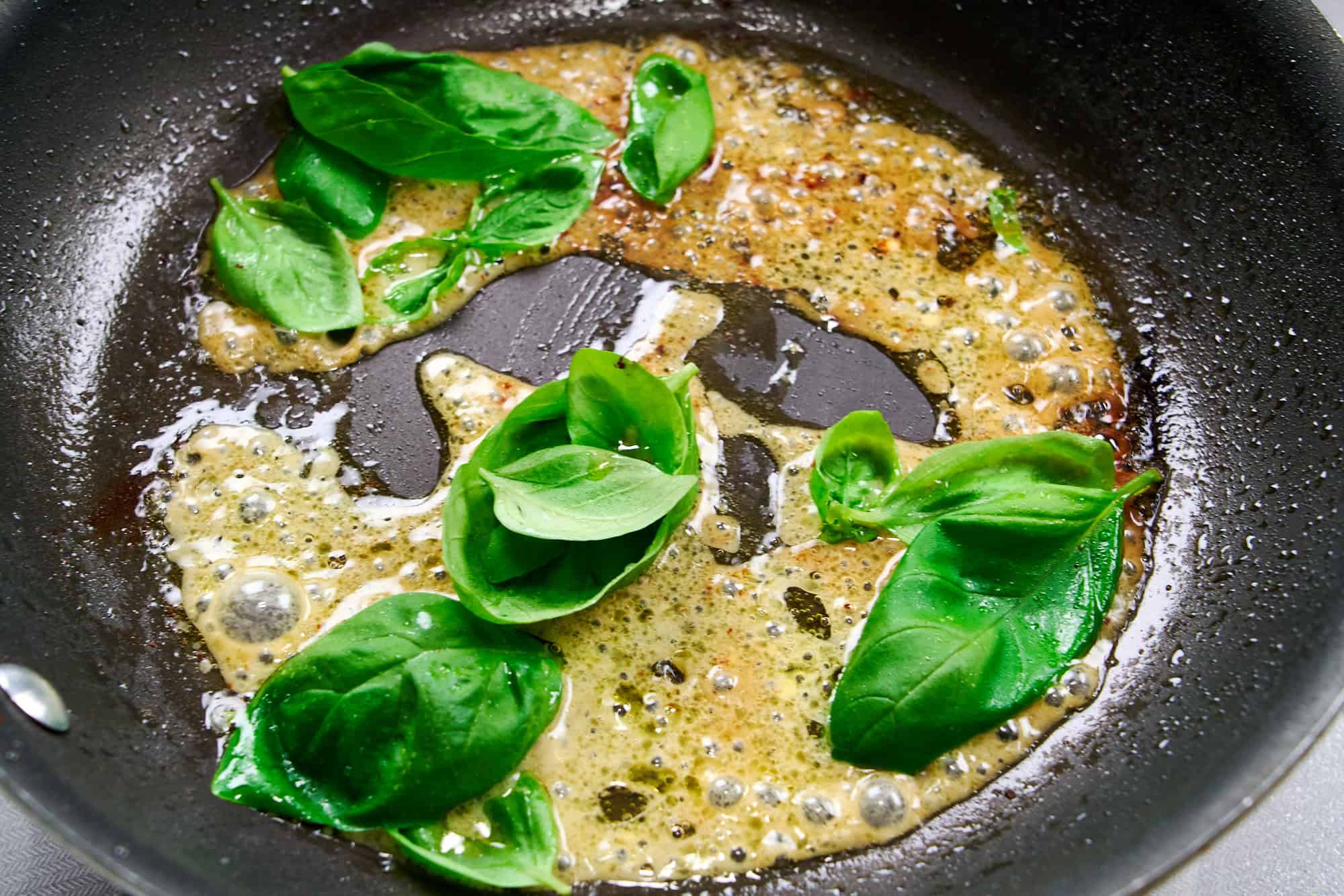 Basil leaves and dressing deglaze the pan.
