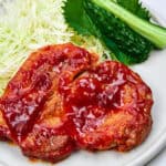 Tangy glazed pork chops on a plate with shredded cabbage and shiso.
