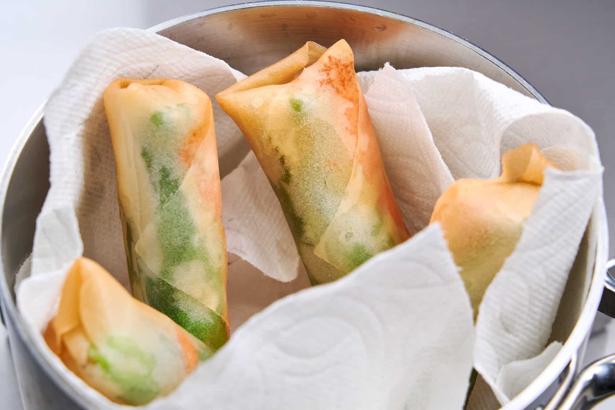 Draining the spring rolls vertically in a saucepan.