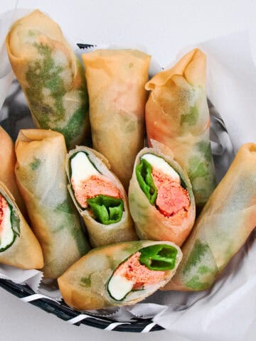 Delicately crispy Mentaiko Cheese Spring Rolls in a basket.