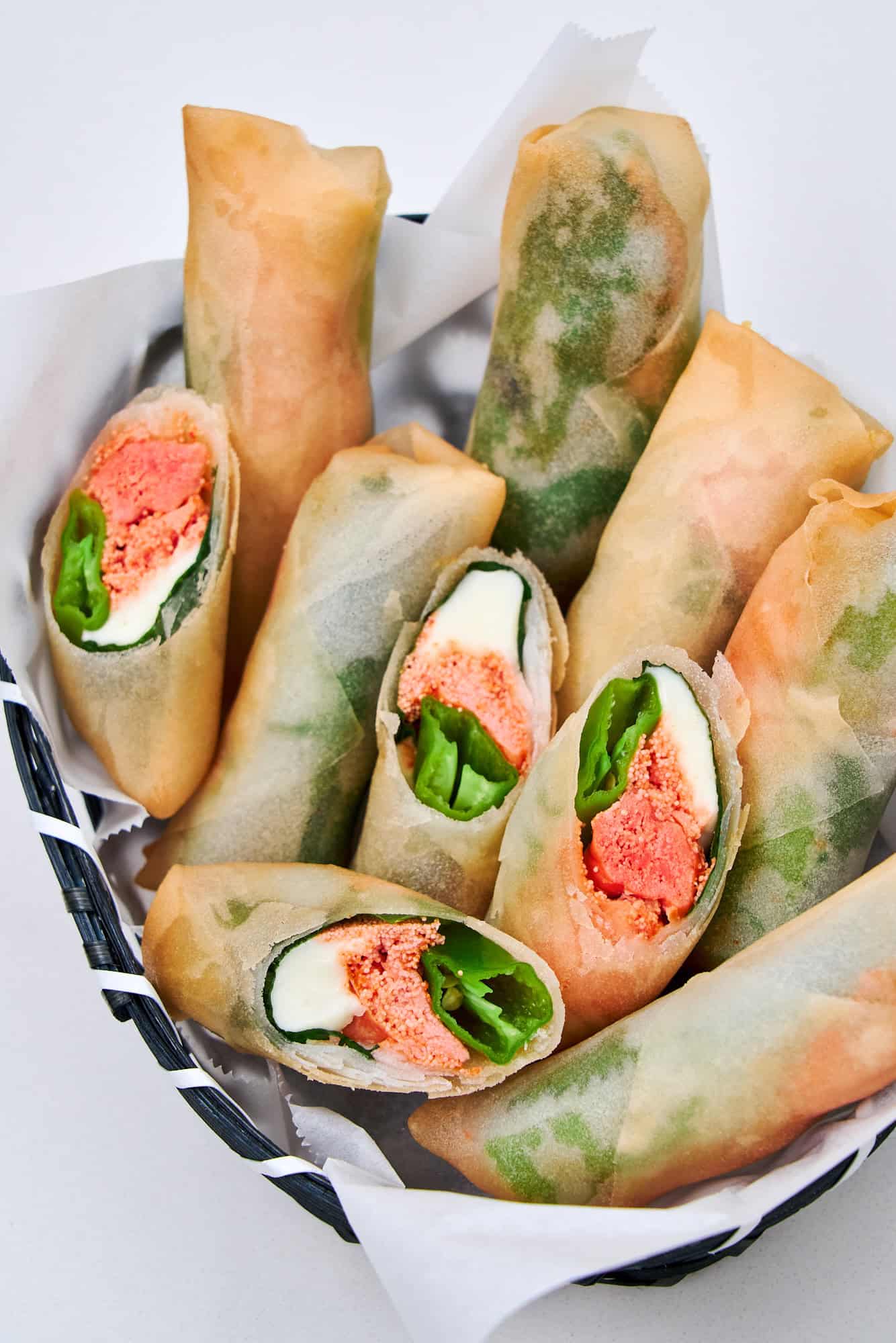 Delicately crispy Mentaiko Cheese Spring Rolls in a basket.